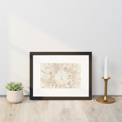 A framed art print with a black frame and white mat, featuring a delicate beige line drawing of a candle surrounded by flowers. The frame is styled on a light wood floor next to a small potted succulent and a gold candlestick holder with a white candle.
