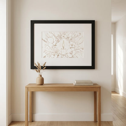 A framed botanical art print with a black frame and white mat, hanging on a beige wall above a light wood console table with a vase and books.