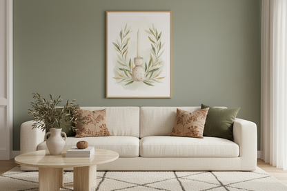 A framed botanical art print featuring a hanging gourd and olive branches, displayed on a sage green wall above a cream-colored sofa with decorative pillows in a styled living room.