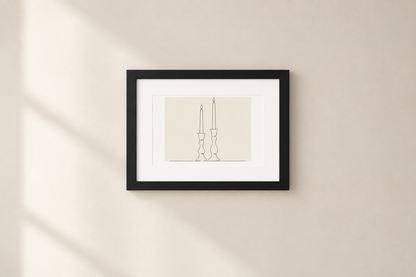 A minimalist black-framed art print featuring a thin line drawing of two candlesticks on a cream background, mounted on a warm beige wall with soft diagonal shadows.